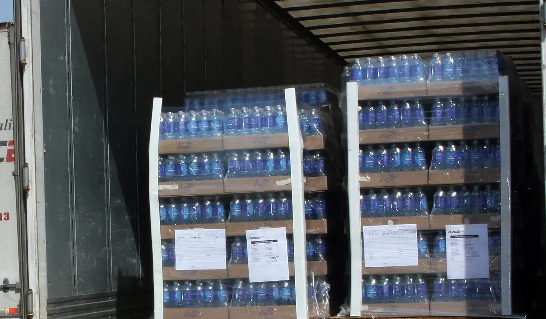 Two shrink-wrapped pallets of bottled beverages loaded at the rear of a dry van trailer
